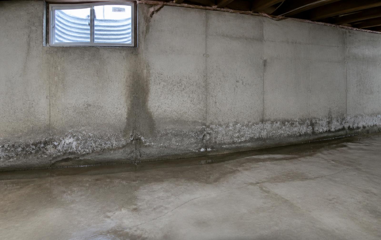 Ohio basement with water seepage staining and standing moisture along the concrete wall-floor joint